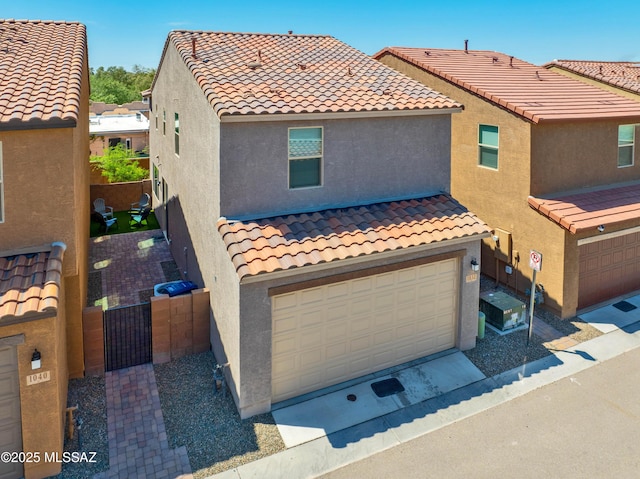 view of front of house with a garage, a residential view, a tile roof, and stucco siding