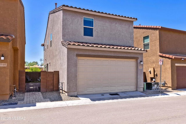 view of front of property featuring a garage, a gate, a tile roof, and stucco siding