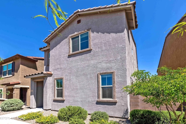 view of property exterior with a tile roof and stucco siding