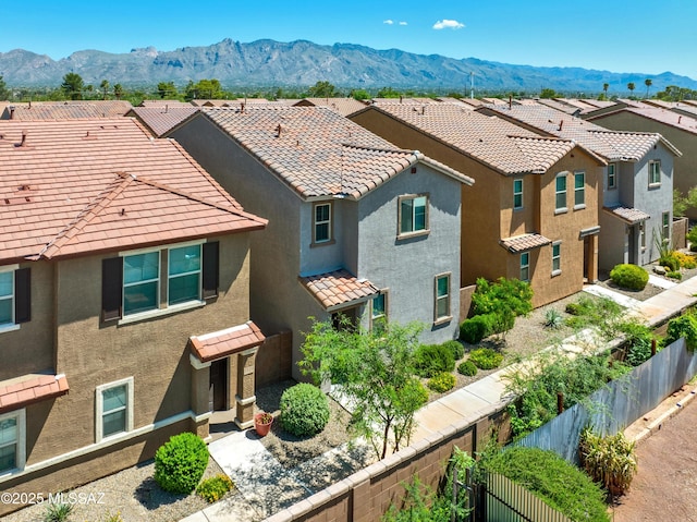 view of front of home with stucco siding, fence, a mountain view, a residential view, and a tiled roof