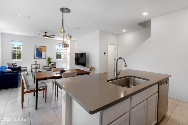 kitchen featuring pendant lighting, a center island with sink, dark countertops, open floor plan, and dishwasher