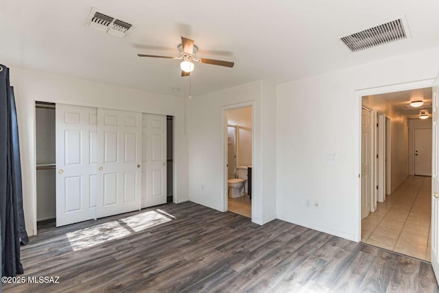 unfurnished bedroom with a closet, ensuite bath, dark hardwood / wood-style floors, and ceiling fan