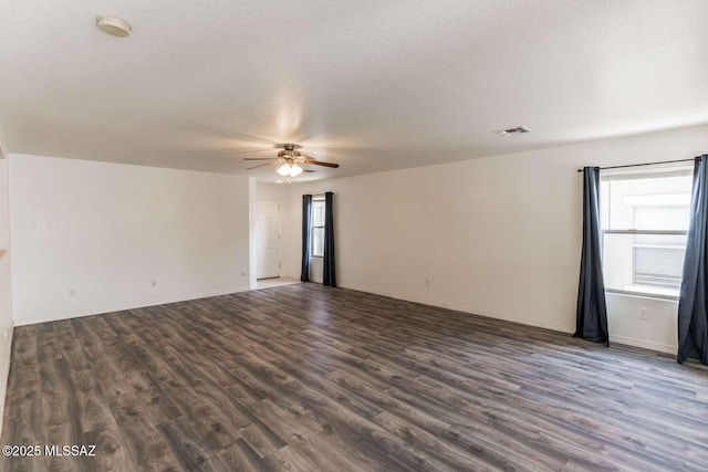 spare room featuring dark hardwood / wood-style flooring, a textured ceiling, and a wealth of natural light