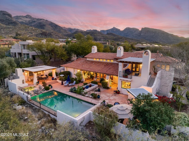 rear view of house featuring a balcony, a patio area, a mountain view, and stucco siding