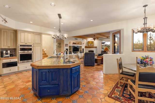 kitchen with a fireplace, a warming drawer, blue cabinetry, double oven, and a sink