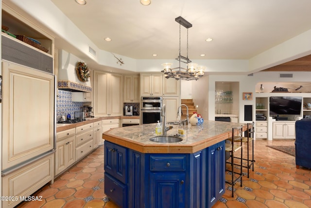 kitchen featuring visible vents, open floor plan, custom exhaust hood, blue cabinetry, and a sink