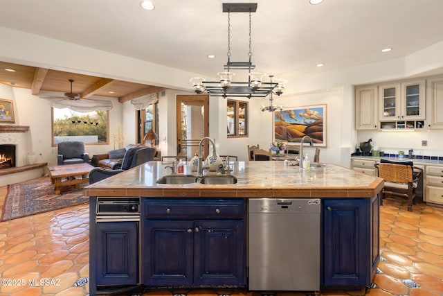 kitchen featuring dishwasher, blue cabinetry, open floor plan, and a sink