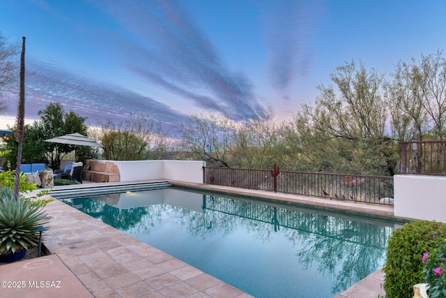 pool at dusk featuring a fenced in pool, a patio area, and fence