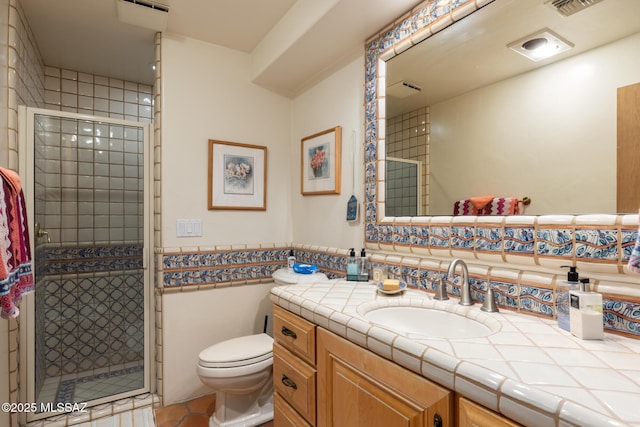 bathroom featuring toilet, a stall shower, wainscoting, and vanity