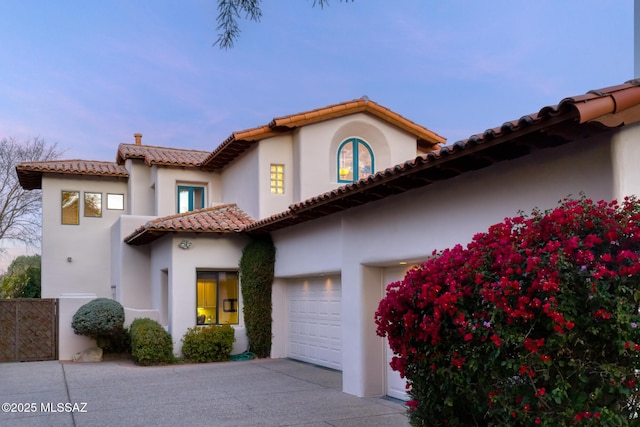 mediterranean / spanish house with driveway, an attached garage, and stucco siding