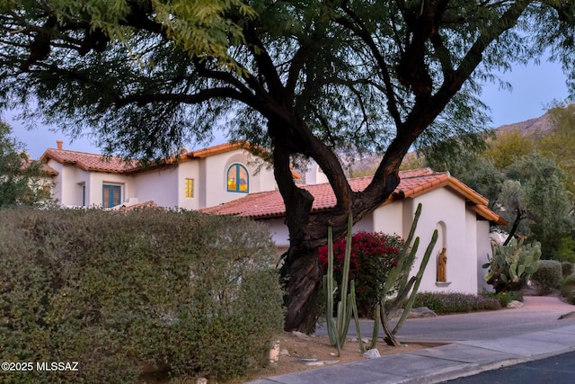 mediterranean / spanish house featuring a tile roof and stucco siding