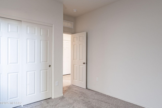 unfurnished bedroom featuring light carpet and a closet