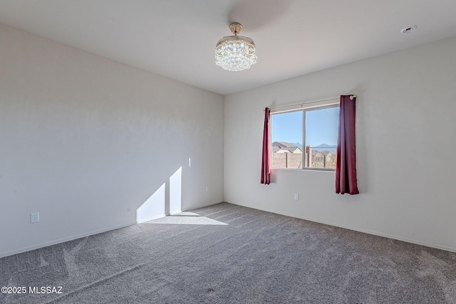 spare room with an inviting chandelier and carpet