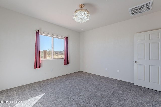 empty room with carpet flooring and a notable chandelier