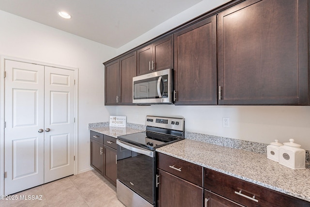 kitchen featuring light stone counters, dark brown cabinetry, appliances with stainless steel finishes, and light tile patterned floors