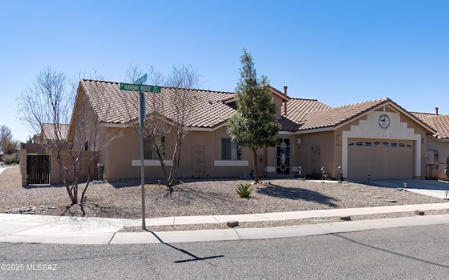 view of front facade with a tiled roof, an attached garage, and stucco siding