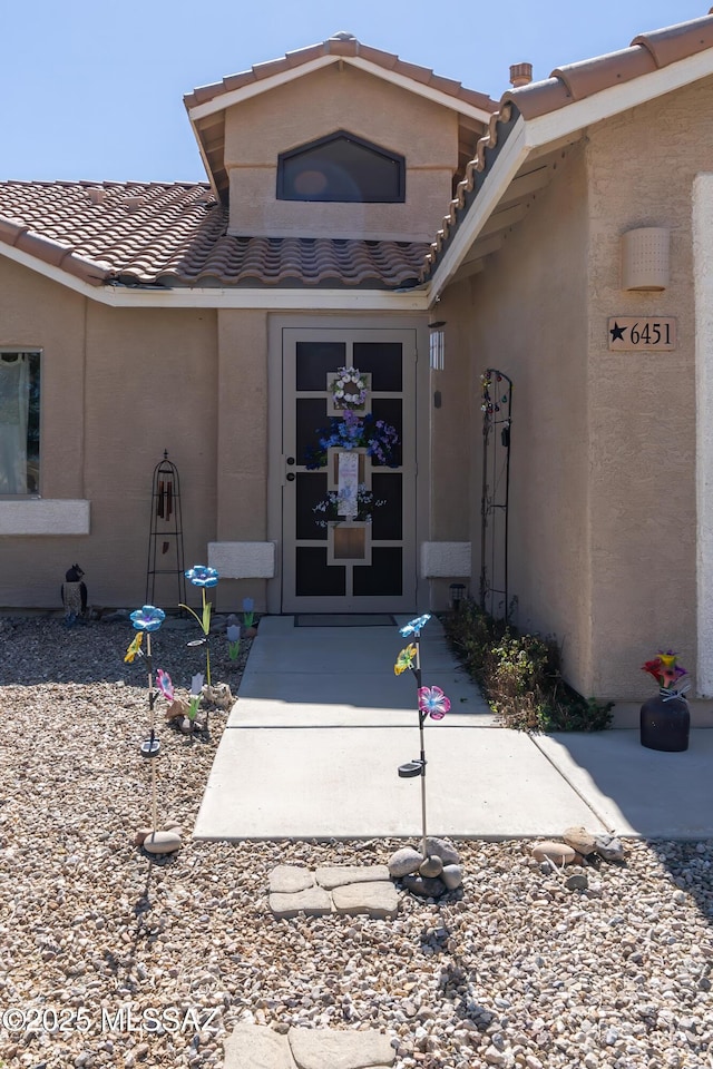 doorway to property featuring a tile roof and stucco siding