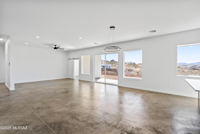 unfurnished living room featuring ceiling fan, a barn door, and a mountain view