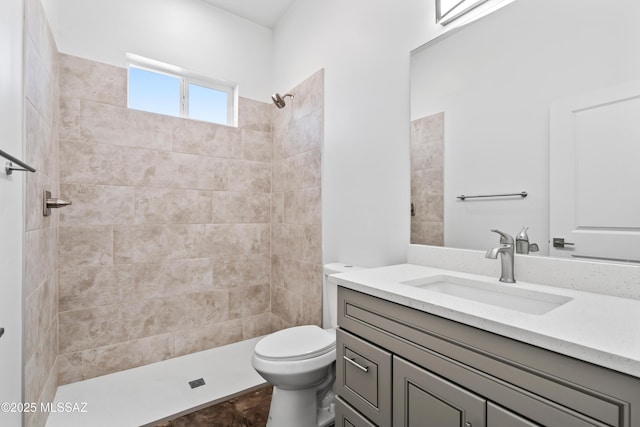 bathroom featuring vanity, tiled shower, and toilet