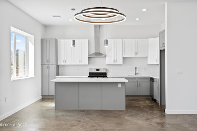 kitchen featuring gray cabinetry, a kitchen island, wall chimney exhaust hood, and appliances with stainless steel finishes