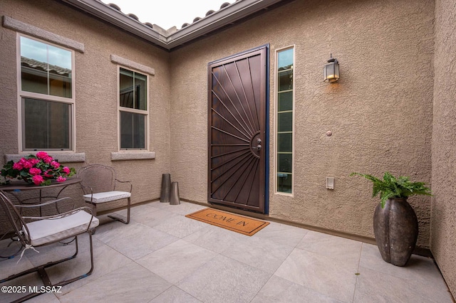 view of exterior entry with a patio and stucco siding