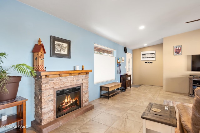 living room featuring a stone fireplace and vaulted ceiling