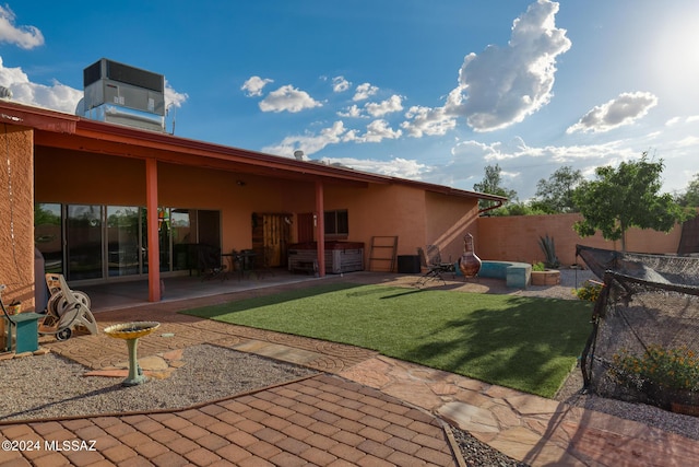 rear view of house featuring central AC, a patio area, a hot tub, and a lawn