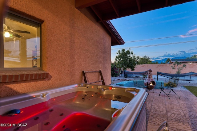 patio terrace at dusk with a mountain view and a hot tub