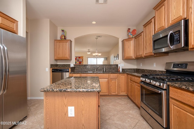 kitchen with a kitchen island, appliances with stainless steel finishes, an inviting chandelier, light tile patterned flooring, and a sink