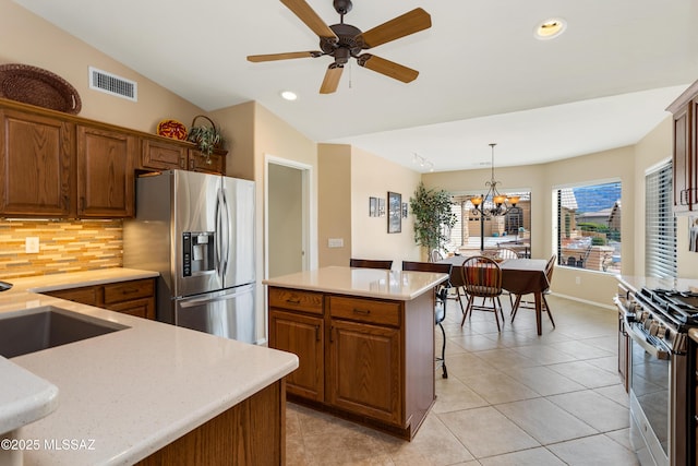 kitchen with vaulted ceiling, hanging light fixtures, a kitchen island, stainless steel appliances, and backsplash