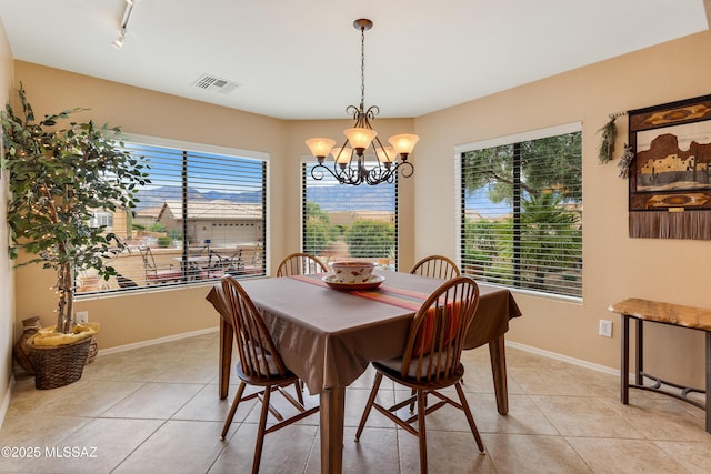 tiled dining space featuring plenty of natural light, rail lighting, and a chandelier