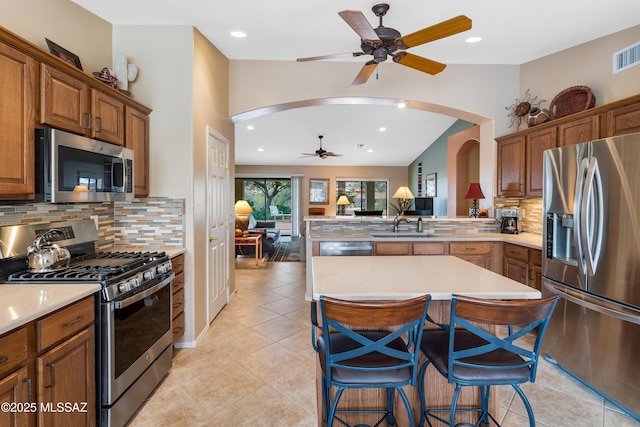 kitchen featuring sink, light tile patterned floors, appliances with stainless steel finishes, a kitchen breakfast bar, and decorative backsplash