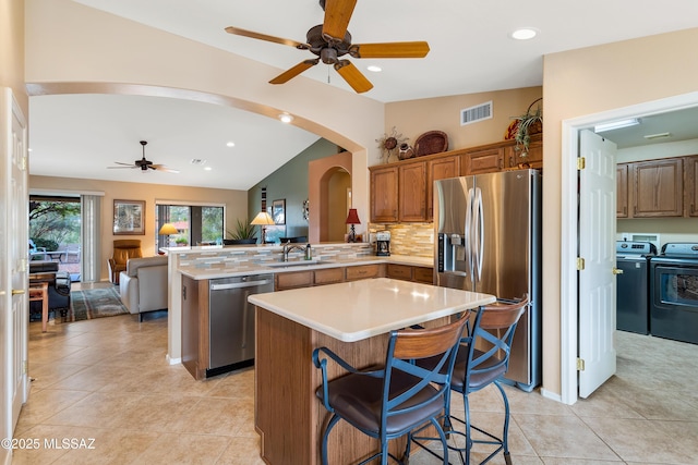 kitchen featuring a kitchen island, a breakfast bar, sink, kitchen peninsula, and stainless steel appliances