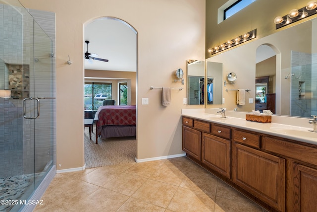 bathroom featuring a shower with door, ceiling fan, a towering ceiling, vanity, and tile patterned floors