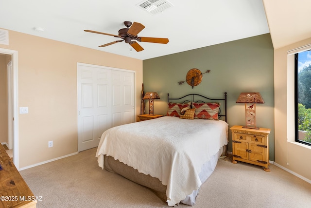 bedroom featuring light colored carpet, ceiling fan, and a closet