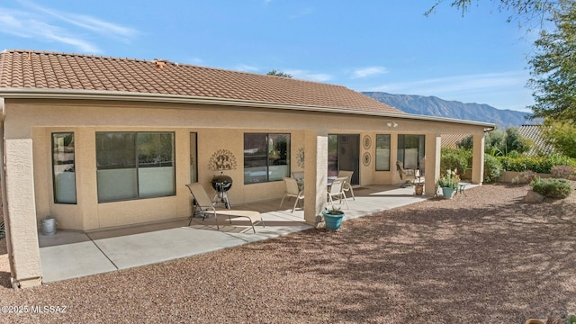 back of house with a mountain view and a patio