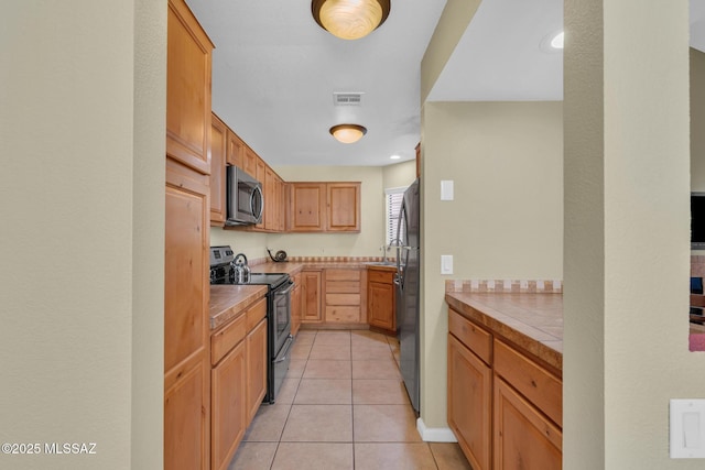 kitchen featuring light tile patterned flooring, appliances with stainless steel finishes, sink, and tile counters