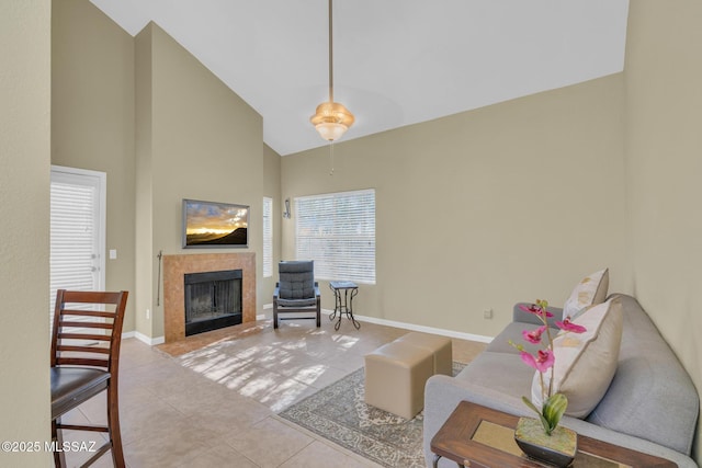 living room with a tiled fireplace, light tile patterned flooring, and high vaulted ceiling