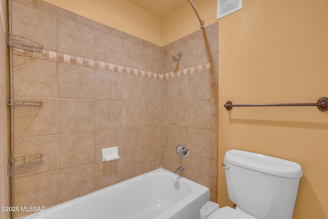 bathroom featuring tiled shower / bath and toilet