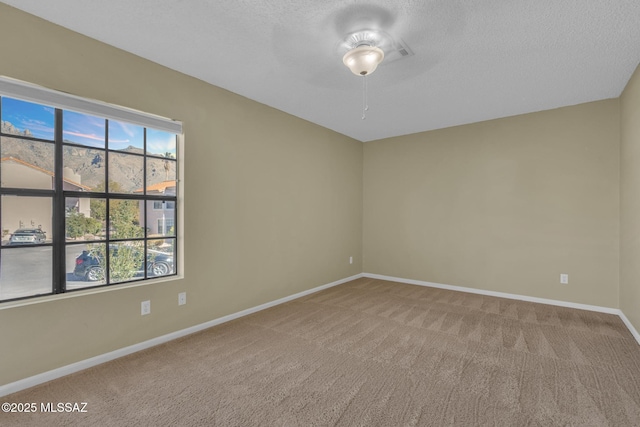 carpeted empty room featuring a mountain view and a textured ceiling