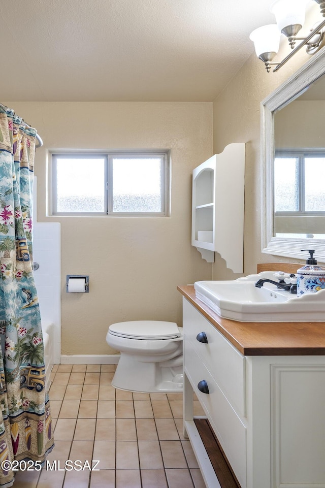 full bathroom featuring vanity, a healthy amount of sunlight, tile patterned floors, and toilet