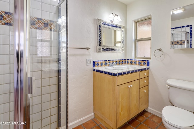 bathroom with a shower with door, vanity, tile patterned floors, and toilet