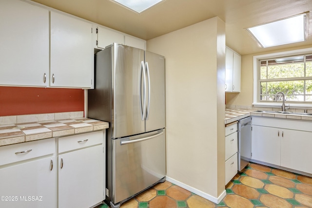 kitchen featuring sink, tile counters, stainless steel appliances, and white cabinets