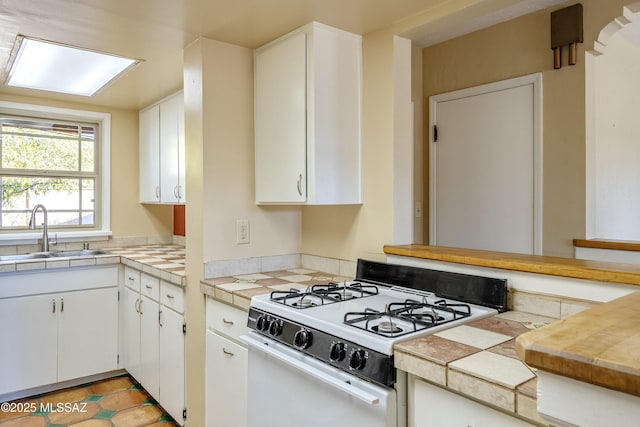 kitchen featuring sink, white gas stove, and white cabinets