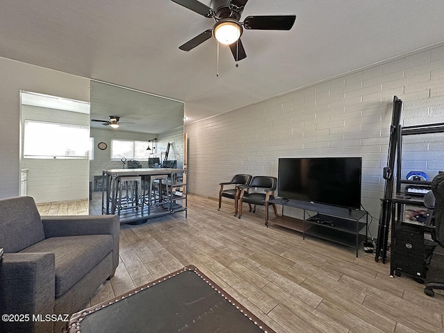 living room with ceiling fan, brick wall, and light wood-type flooring