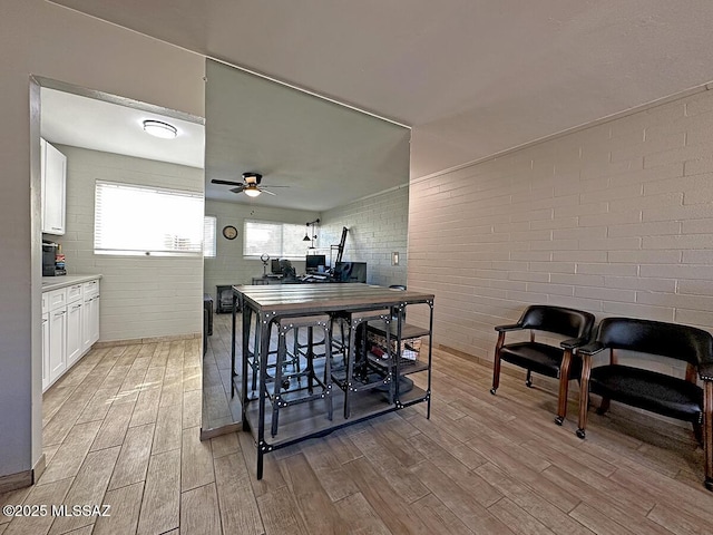 interior space featuring ceiling fan and brick wall