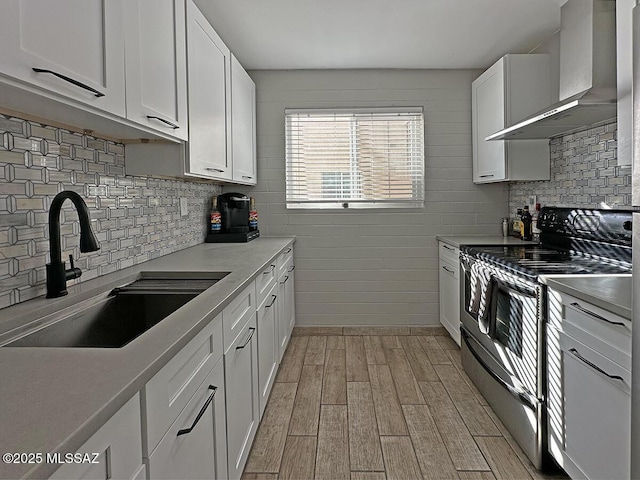 kitchen featuring white cabinets, sink, wall chimney range hood, and electric range