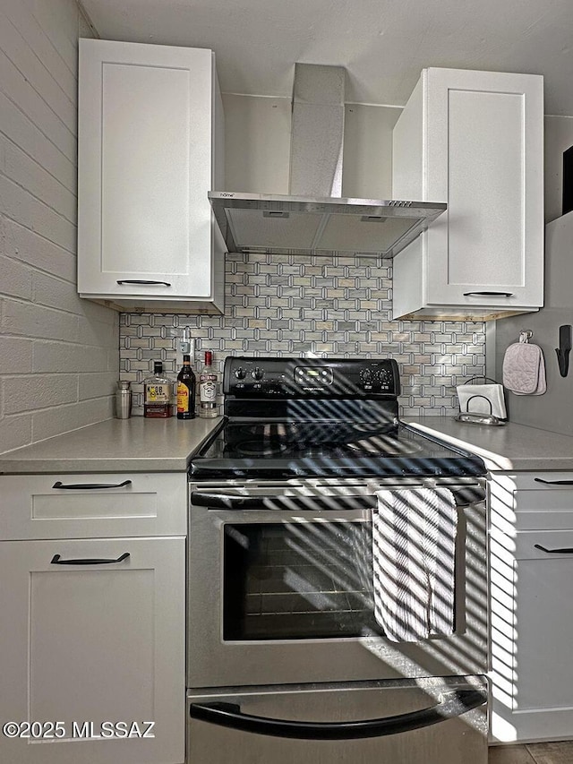 kitchen featuring white cabinets, electric range, decorative backsplash, and wall chimney exhaust hood