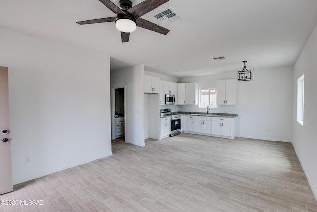 kitchen with sink, white cabinetry, light hardwood / wood-style flooring, appliances with stainless steel finishes, and pendant lighting