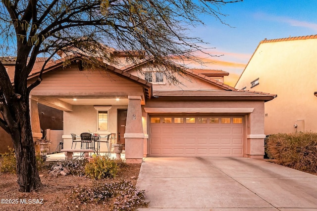 view of front of house featuring a garage, driveway, a tile roof, and stucco siding